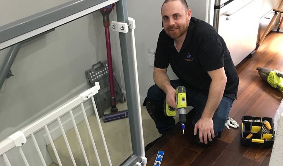 Gil Redden installing a safety gate on a glass railing in a Vancouver home